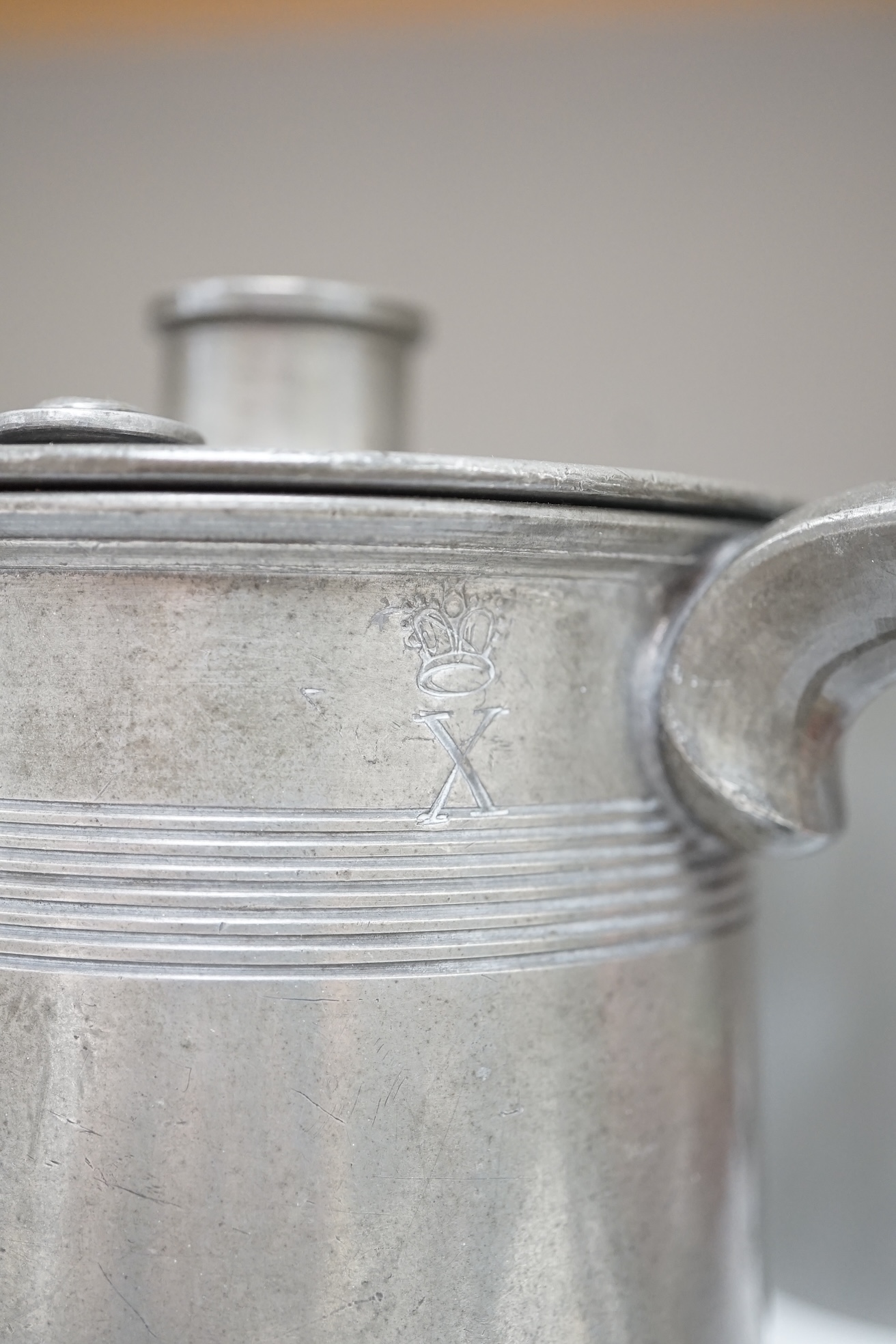 Six items of 18th century and later pewter including a jug, candlesticks, a pint measure, and a bronze hand bell, 24cm high. Condition - fair.